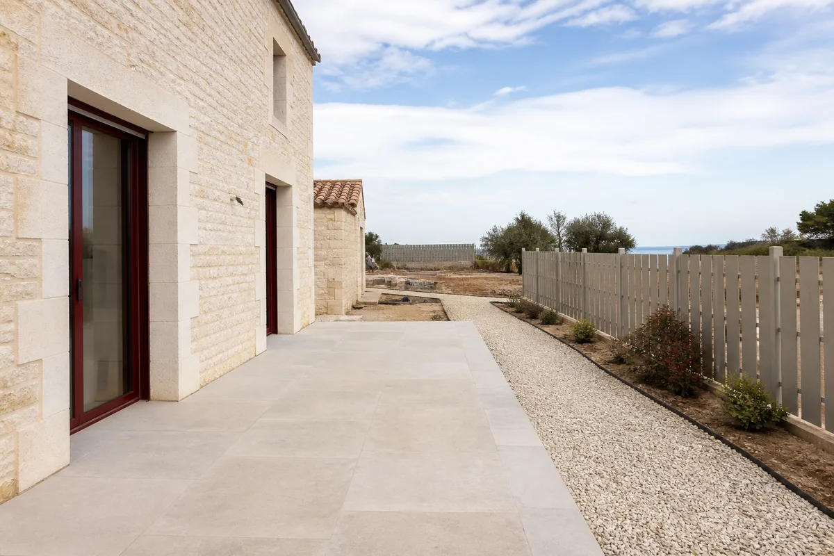 Terrasse en dalles bordée d’une allée en gravier et d’une clôture claire
